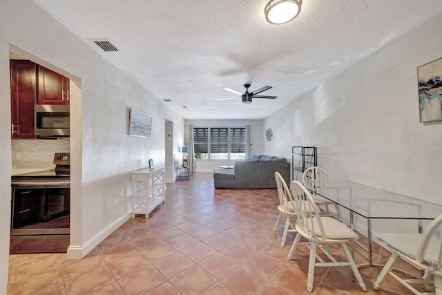 dining area featuring ceiling fan, light tile patterned flooring, and a textured ceiling