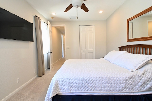 bedroom with ceiling fan, light colored carpet, and a closet