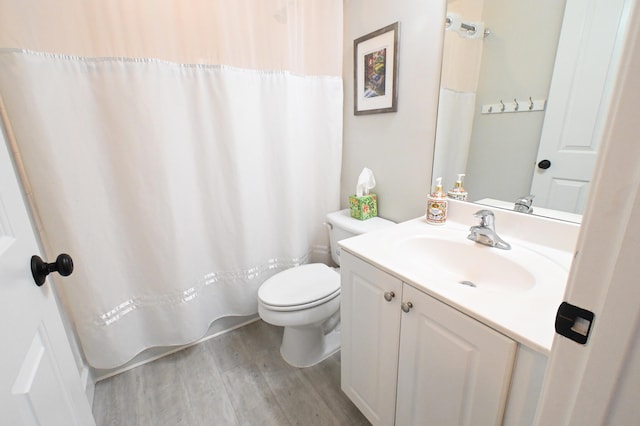 bathroom with hardwood / wood-style floors, toilet, vanity, and curtained shower