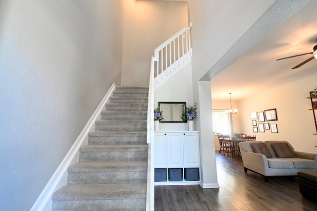 stairway featuring wood-type flooring and ceiling fan with notable chandelier