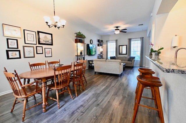 dining room featuring ceiling fan with notable chandelier and dark hardwood / wood-style flooring