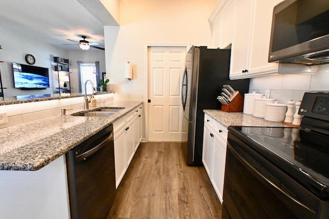 kitchen with white cabinets, sink, stone countertops, light hardwood / wood-style flooring, and stainless steel appliances