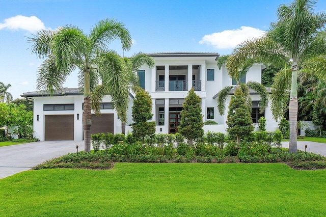 view of front of property with a balcony, a front yard, and a garage