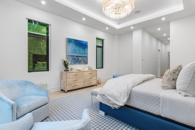 bedroom featuring an inviting chandelier, multiple windows, a raised ceiling, and hardwood / wood-style floors