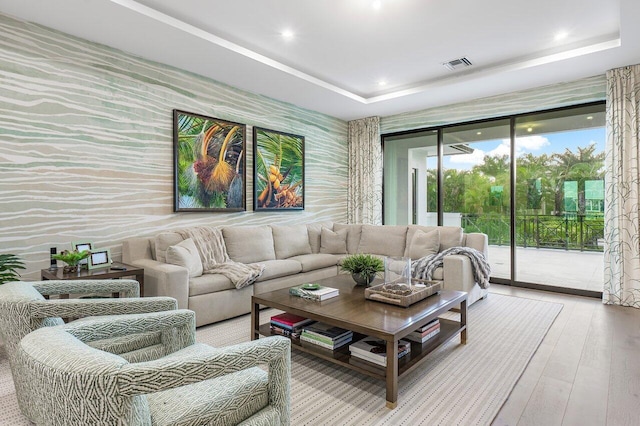 living room with light hardwood / wood-style floors, a tray ceiling, and french doors