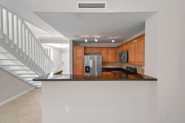 kitchen with backsplash, kitchen peninsula, dark stone countertops, and appliances with stainless steel finishes