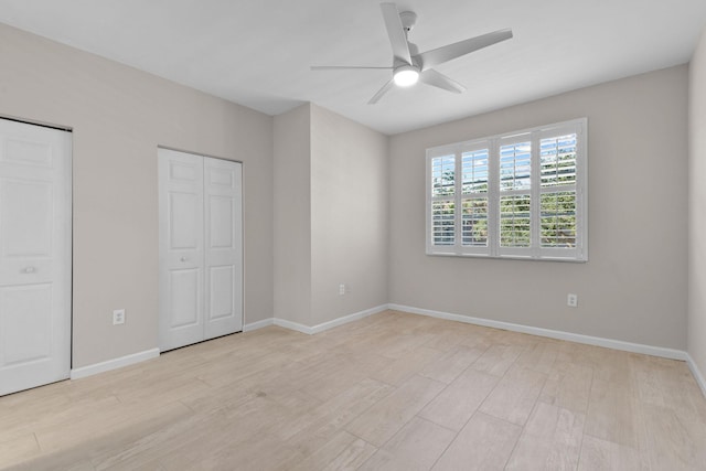 unfurnished bedroom featuring light wood-type flooring, ceiling fan, and multiple closets