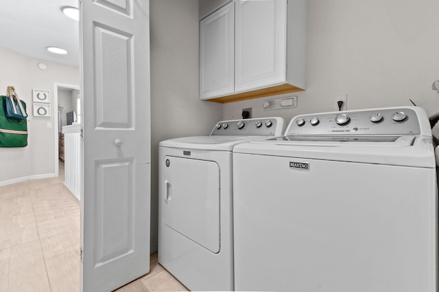 laundry room with cabinets, light tile patterned floors, and washing machine and clothes dryer