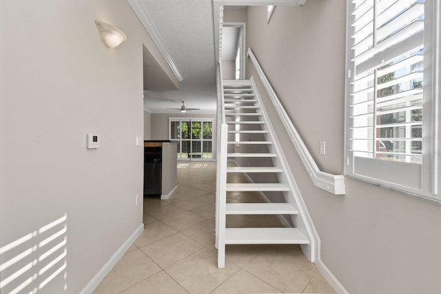 stairway with tile patterned flooring, a textured ceiling, ceiling fan, and ornamental molding