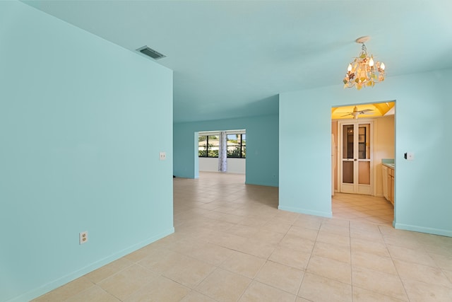 spare room featuring a notable chandelier and light tile patterned floors