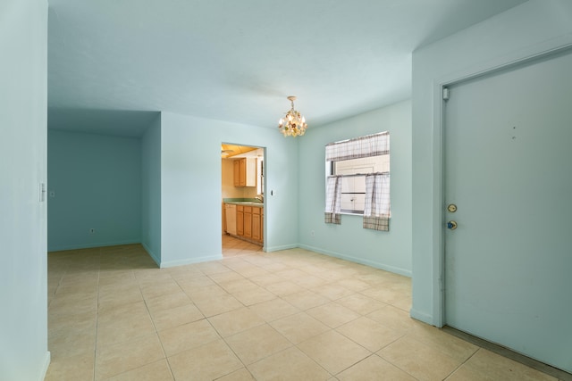 empty room featuring light tile patterned flooring, sink, and a chandelier