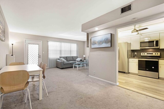 interior space with light hardwood / wood-style floors, tasteful backsplash, white cabinetry, appliances with stainless steel finishes, and ceiling fan