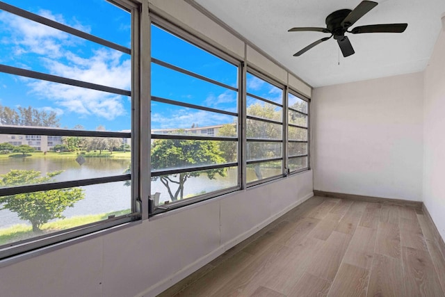 unfurnished sunroom with a water view and ceiling fan