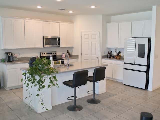 kitchen with a kitchen island with sink, white cabinetry, and stainless steel appliances