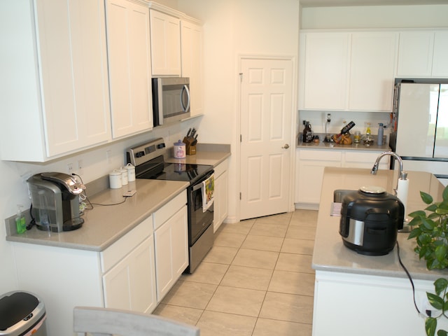 kitchen featuring appliances with stainless steel finishes, white cabinetry, and light tile patterned floors