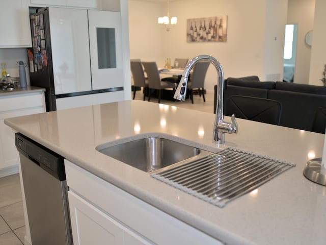 kitchen featuring decorative light fixtures, stainless steel dishwasher, white cabinets, and white refrigerator