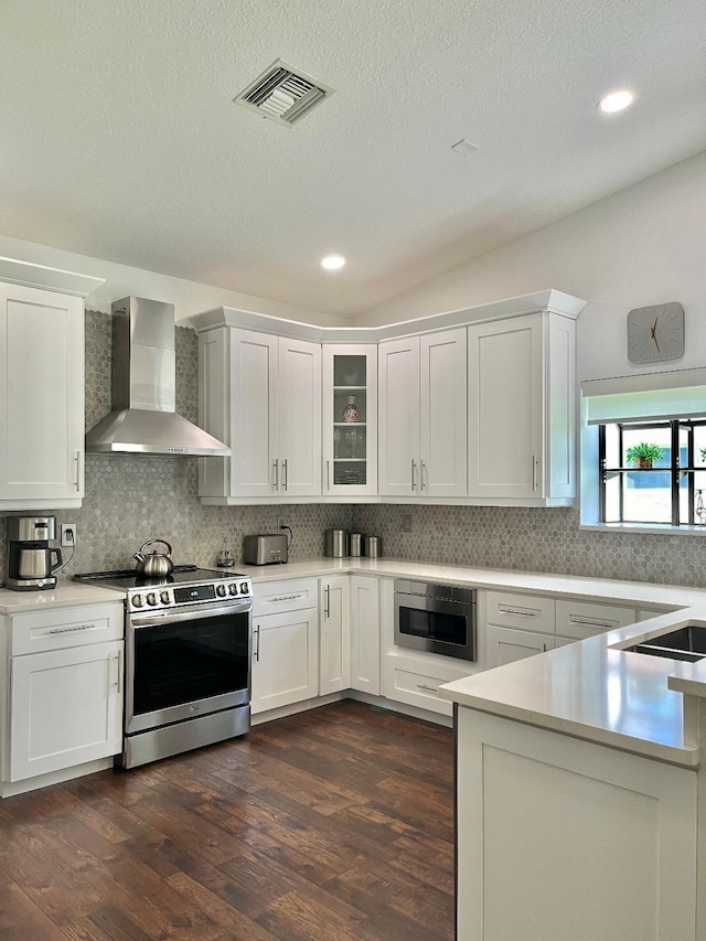 kitchen featuring wall chimney exhaust hood, appliances with stainless steel finishes, dark hardwood / wood-style floors, white cabinets, and backsplash