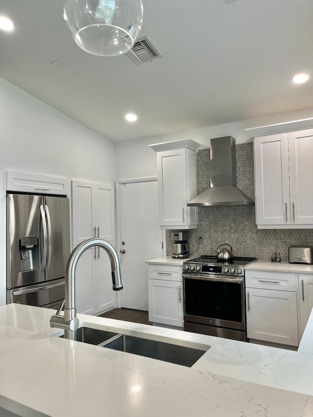 kitchen featuring stainless steel appliances, sink, wall chimney range hood, and white cabinets