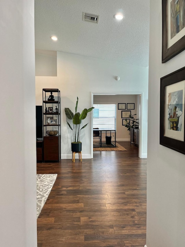 hallway with dark wood-type flooring and a textured ceiling