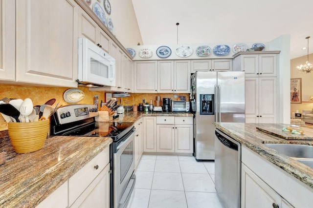 kitchen featuring light tile patterned flooring, lofted ceiling, hanging light fixtures, a chandelier, and stainless steel appliances