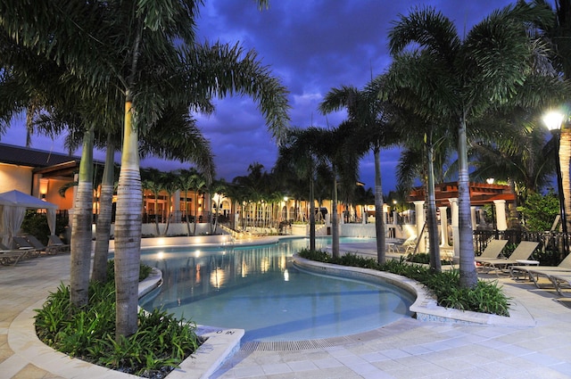 pool at night featuring a patio