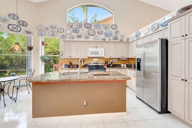 kitchen with a kitchen island with sink, stainless steel appliances, sink, and high vaulted ceiling