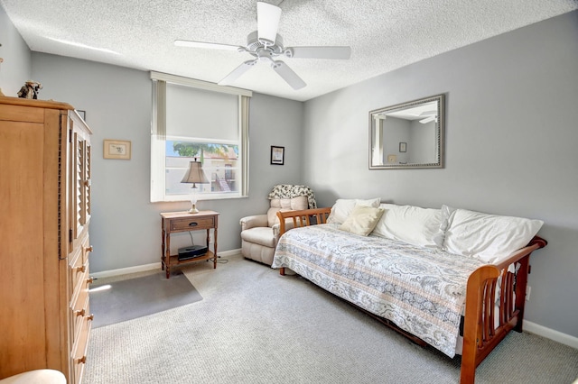 carpeted bedroom featuring ceiling fan and a textured ceiling