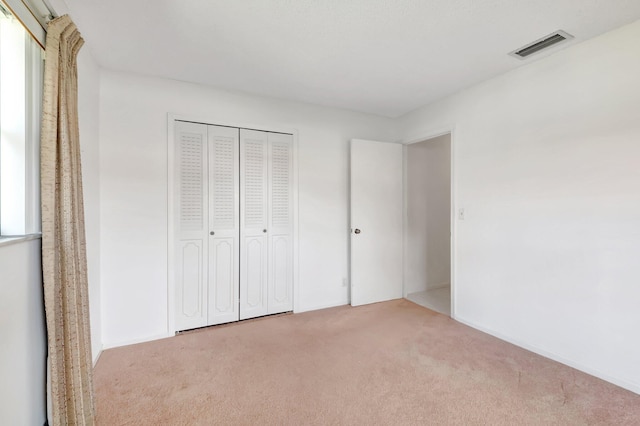 unfurnished bedroom featuring light carpet and a closet