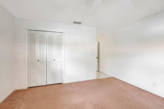 unfurnished bedroom featuring light carpet, ceiling fan, and a closet