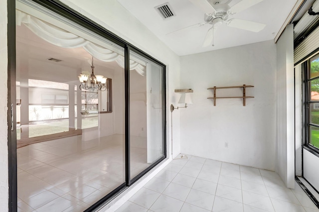 tiled spare room featuring ceiling fan with notable chandelier