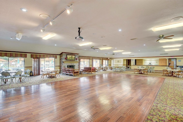 misc room featuring a large fireplace, ceiling fan, and wood-type flooring