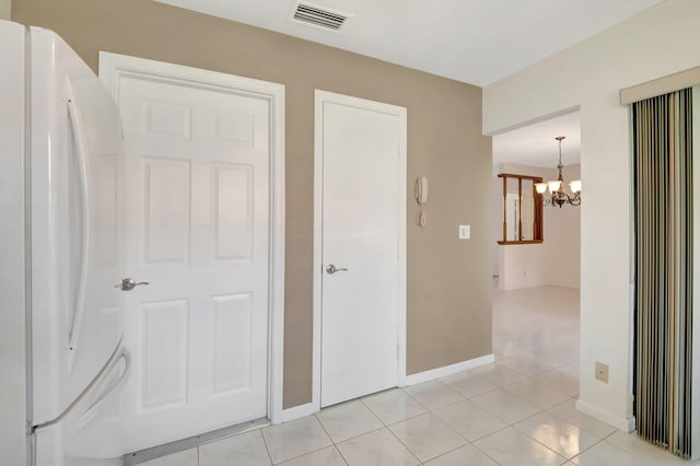 unfurnished bedroom featuring light tile patterned floors, a chandelier, and white refrigerator