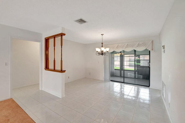 empty room with light tile patterned flooring and a chandelier