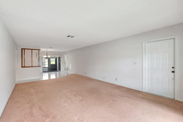 unfurnished living room with light colored carpet and an inviting chandelier