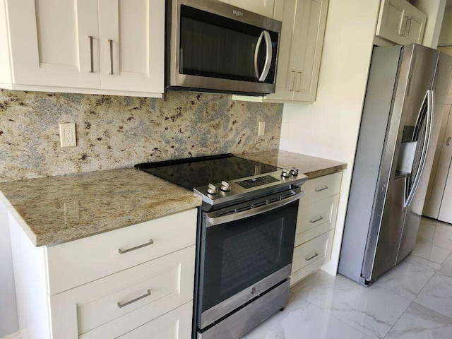 kitchen featuring backsplash, white cabinets, light stone counters, and stainless steel appliances