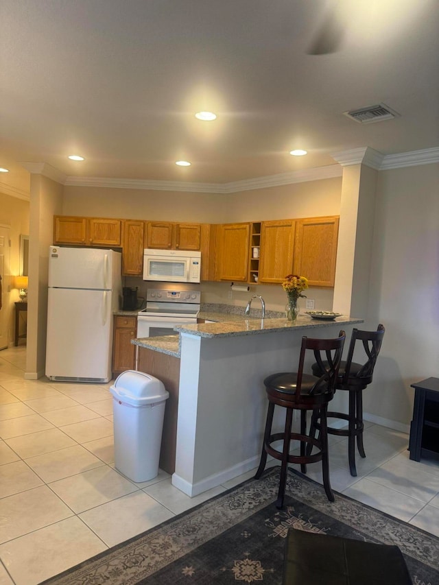 kitchen featuring ornamental molding, a breakfast bar area, kitchen peninsula, and white appliances