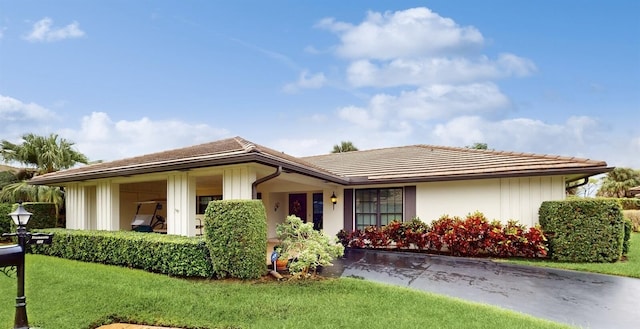 view of front of home featuring board and batten siding, a tiled roof, and a front yard