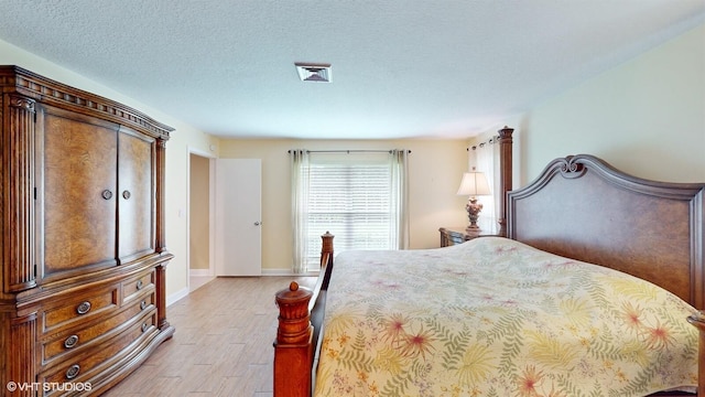bedroom featuring baseboards, light wood-type flooring, and a textured ceiling