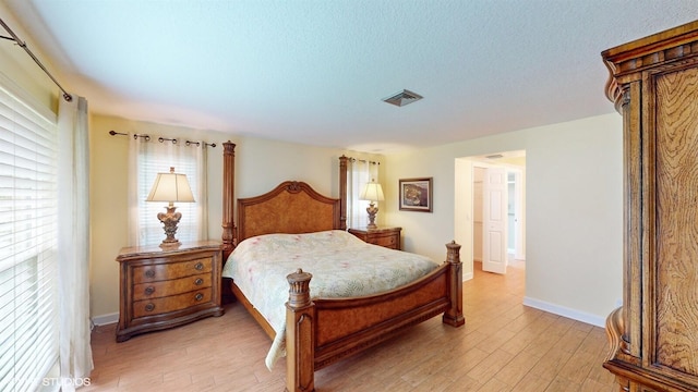 bedroom with light wood-style floors, baseboards, multiple windows, and visible vents
