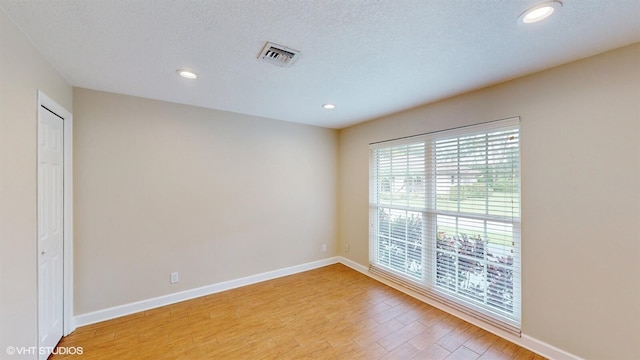 spare room with light wood finished floors, baseboards, visible vents, and recessed lighting