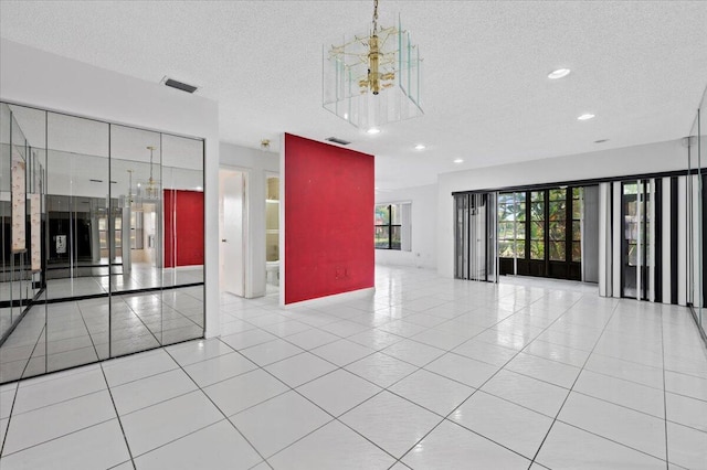 spare room featuring a textured ceiling, light tile patterned floors, and a chandelier