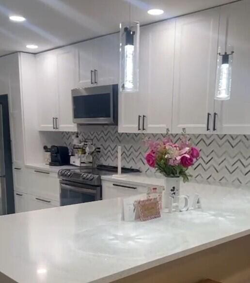 kitchen featuring white cabinets, stainless steel appliances, and decorative light fixtures