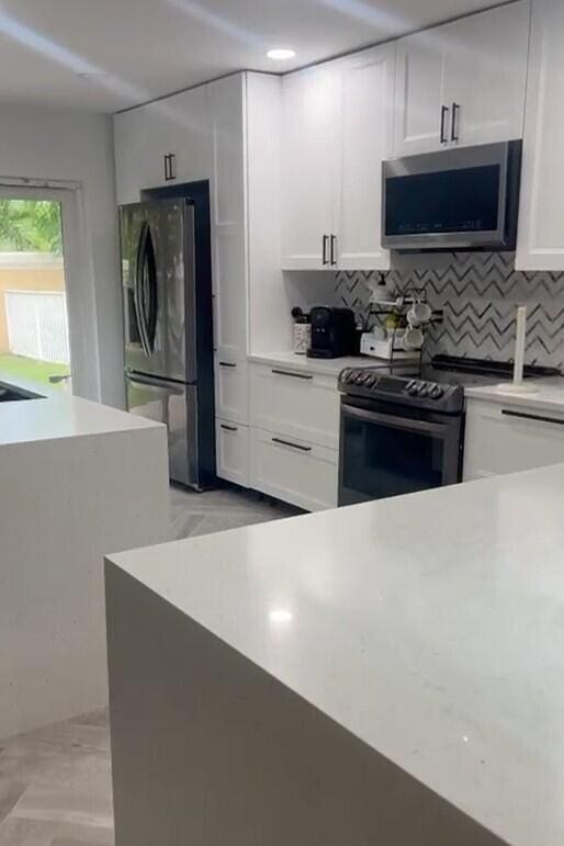 kitchen featuring appliances with stainless steel finishes, backsplash, and white cabinetry