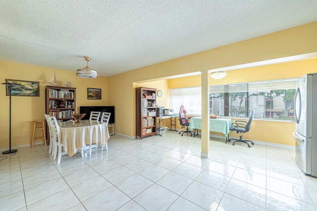 dining space featuring tile patterned floors, a textured ceiling, and a healthy amount of sunlight