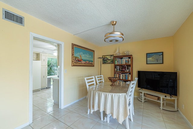 dining space featuring a textured ceiling and light tile patterned floors