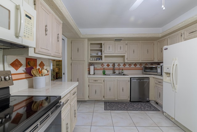 kitchen featuring backsplash, stainless steel appliances, tile countertops, ceiling fan, and sink