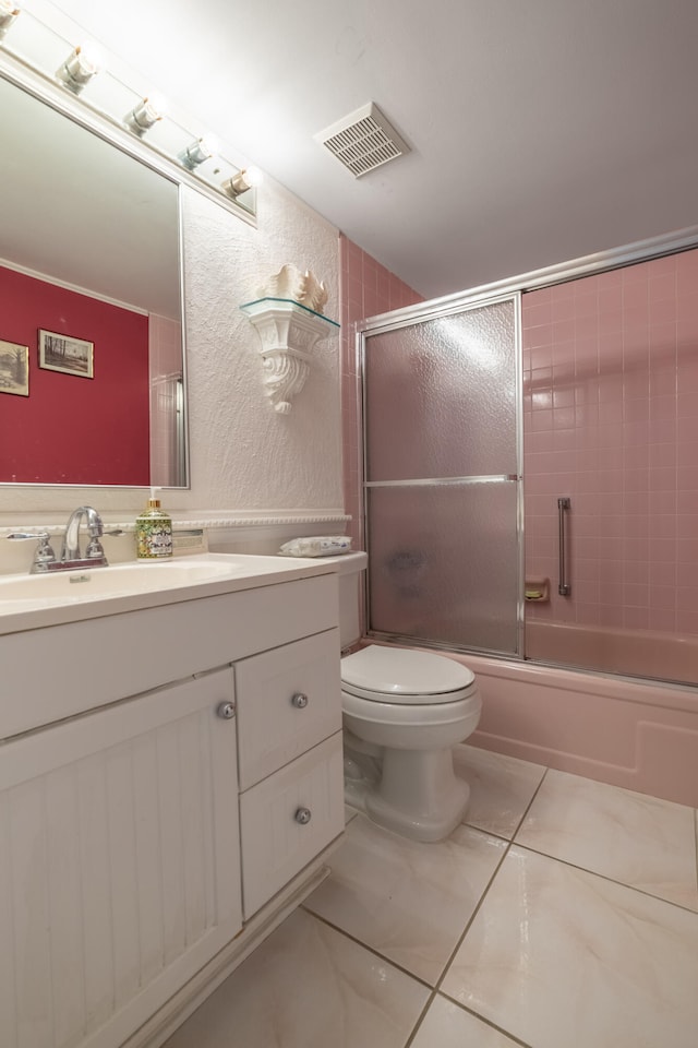 full bathroom with shower / bath combination with glass door, vanity, tile patterned flooring, and toilet