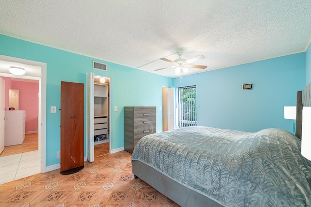 bedroom featuring ceiling fan, a textured ceiling, a closet, and a spacious closet