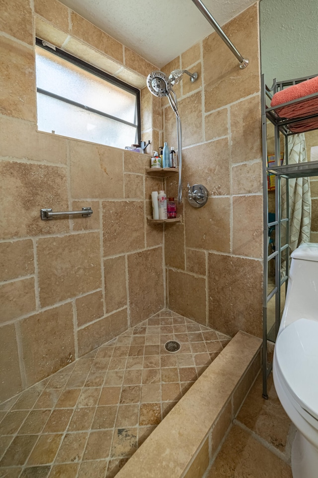 bathroom featuring tiled shower and toilet