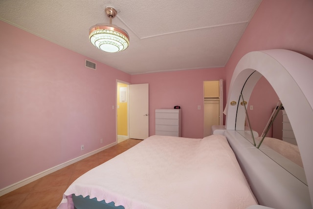 tiled bedroom featuring a spacious closet, a closet, and a textured ceiling